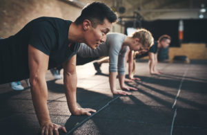 Group of people doing push ups in a gym.