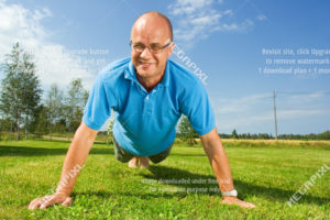 Middle aged man on grass doing push-ups.