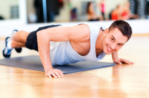 Smiling man doing Push-Ups in a gym.