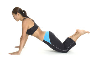 A female fitness instructor demonstrates the finishing position of a kneeling push up.
